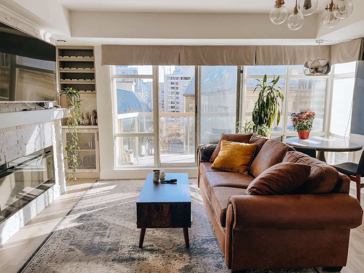 Stylish living room with brown sofa and large windows showcasing a cityscape.